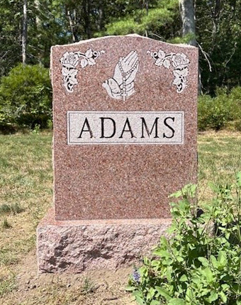 Example of upright headstone made of mountain rose granite that has engraving of praying hands and cultivated roses.